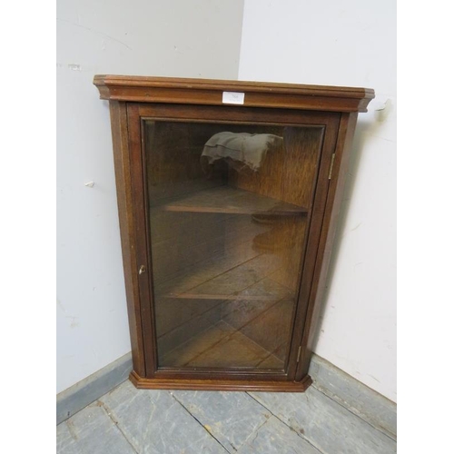 788 - A reproduction mahogany wall hanging glazed corner cupboard, having a moulded cornice above two loos... 