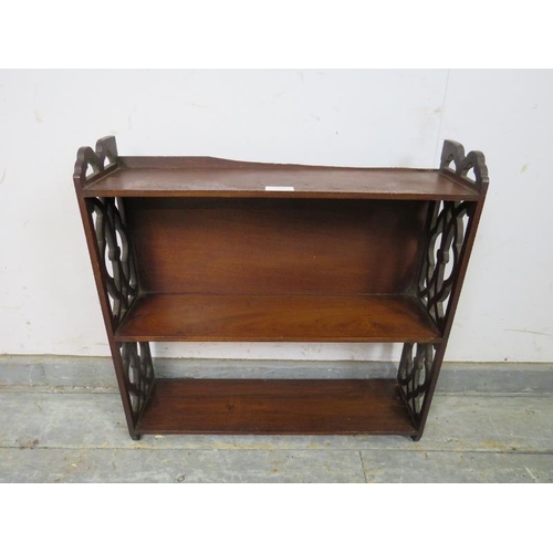 789 - An Edwardian mahogany wall hanging bookshelf, of three open shelves, having pierced fretwork side de... 