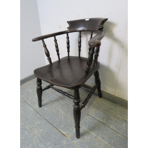 790 - A turn of the century ebonised captain’s chair, carved with the initial ‘M’ the scrolled arms joined... 