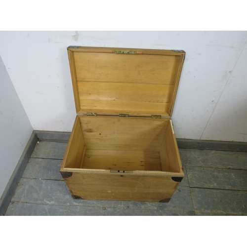 836 - A small vintage pine flat topped trunk, having metal bound corners and recessed handles to either si... 