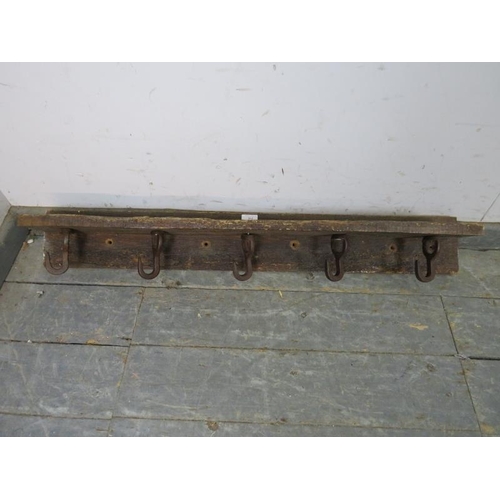 844 - A rustic antique oak wall mounting shelf, fitted with five cast iron rotating coat hooks. 
H14cm W10... 