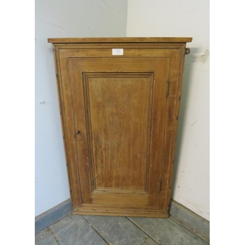 854 - An antique pine wall-hanging corner cupboard, the panelled door opening onto two loose shelves. 
H78... 