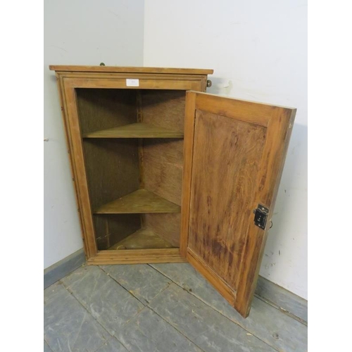 854 - An antique pine wall-hanging corner cupboard, the panelled door opening onto two loose shelves. 
H78... 