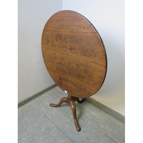 868 - A Georgian oak tilt-top circular supper table, on a tapered turned column with splayed tripod suppor... 