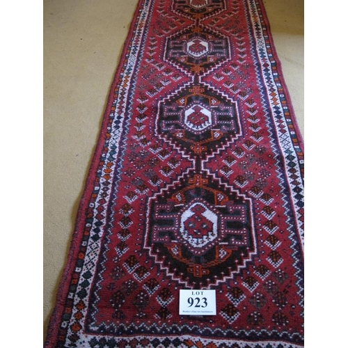 923 - A mid 20th Century Turkish runner.  Five central interlocking medallions on a red ground 290 x 81cms... 