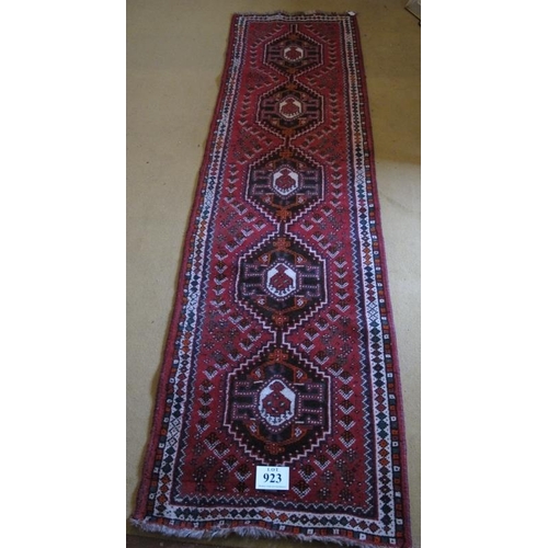 923 - A mid 20th Century Turkish runner.  Five central interlocking medallions on a red ground 290 x 81cms... 