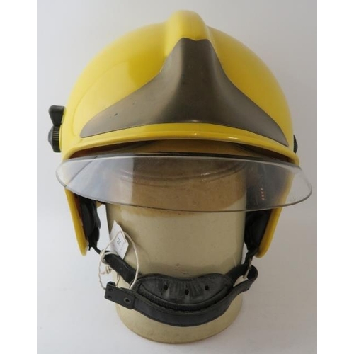 116 - A 1985 CGF Gallet yellow ABS fire helmet with integrated reflective gold visor and brass helmet moun... 