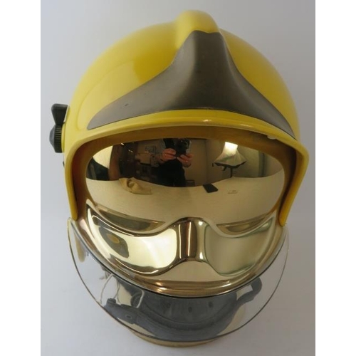 116 - A 1985 CGF Gallet yellow ABS fire helmet with integrated reflective gold visor and brass helmet moun... 