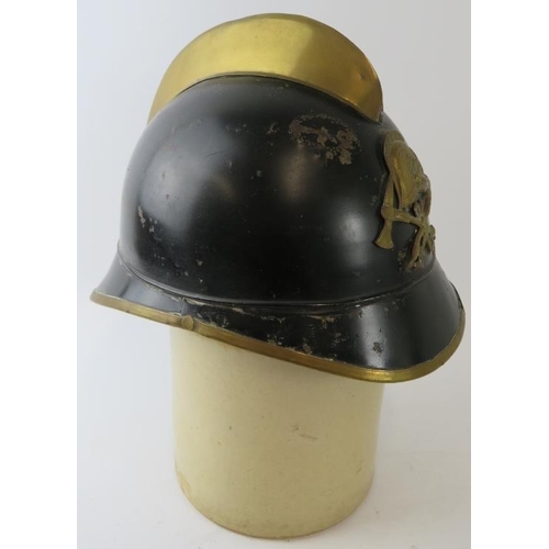 58 - A 1930s German black and brass fire helmet with crossed axe badge