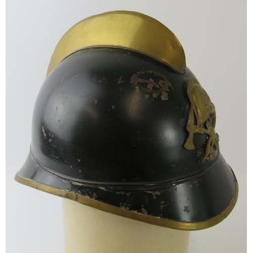 58 - A 1930s German black and brass fire helmet with crossed axe badge