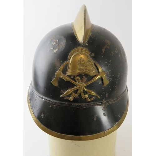 58 - A 1930s German black and brass fire helmet with crossed axe badge