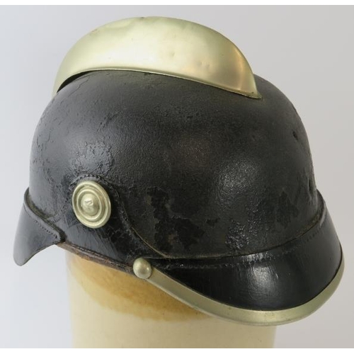 59 - An early 20th century German black leather fire helmet with white metal mounts