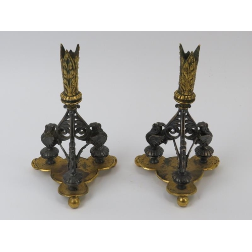 136 - A pair of gilt metal and silver plated triform candlesticks, 19th century. Modelled with mythical be... 