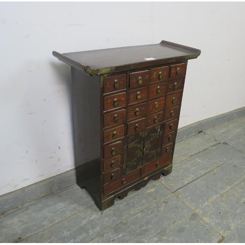 725 - A vintage Chinese elm brass mounted apothecary cabinet, having a configuration of 23 short drawers c... 