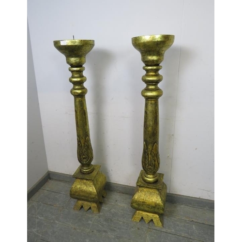 748 - A matched pair of floor-standing giltwood candlesticks, the turned columns with carved acanthus deco... 