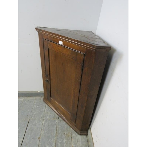 854 - A Georgian oak wall-hanging corner cupboard, the panelled door opening onto two fitted shelves. 
H87... 