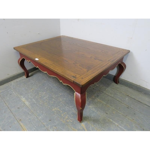 856 - A reproduction oak rectangular coffee table, the burgundy painted base with shaped frieze above ogee... 