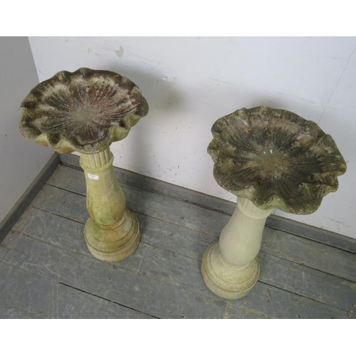 898 - A pair of weathered reconstituted stone birdbaths modelled as shells, on baluster columns.
H80cm Dia... 