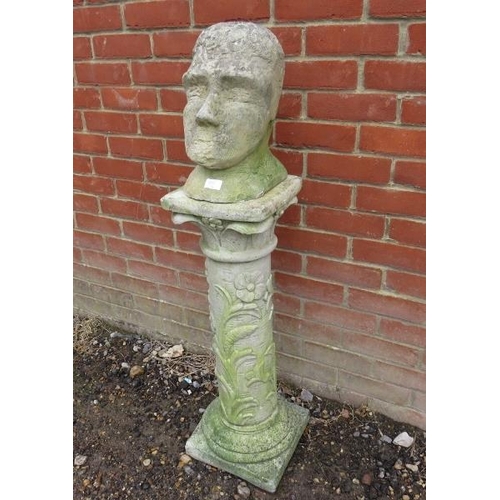 900 - A primitive sandstone sculpture modelled as a head, on an associated reconstituted column with relie... 