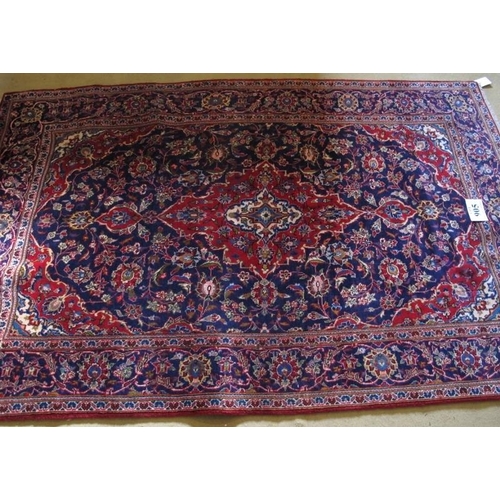 905 - A central Persian Kashan rug. Typical Kashan with central motif.  Red on blue ground.  230cm x 148cm... 