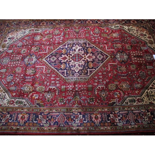 916 - A Persian Tabriz central hexagonal medallion on red ground with wide blue borders. 309cm x 204cm (ap... 