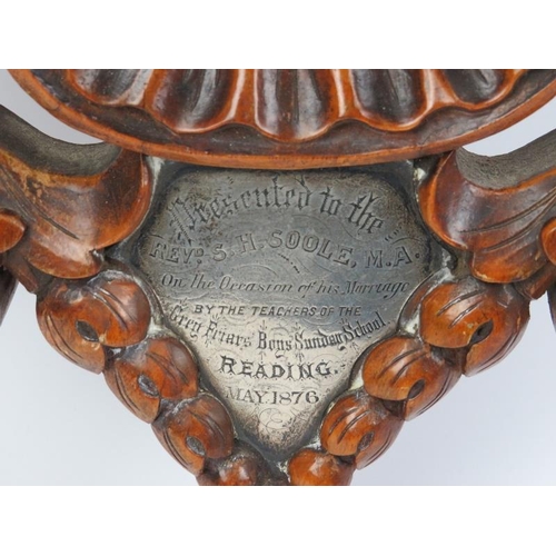 11 - A Victorian foliate carved aneroid barometer with clock. Incorporated with an inscribed presentation... 