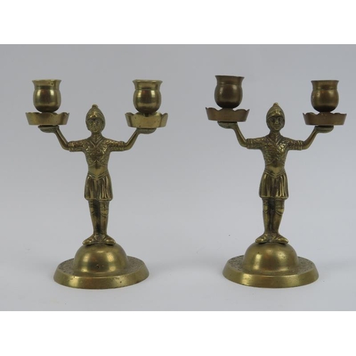 271 - A pair of brass twin branched candlesticks, 19th century. Modeled as warriors holding sconces aloft.... 