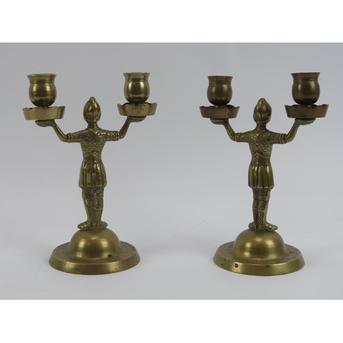 271 - A pair of brass twin branched candlesticks, 19th century. Modeled as warriors holding sconces aloft.... 