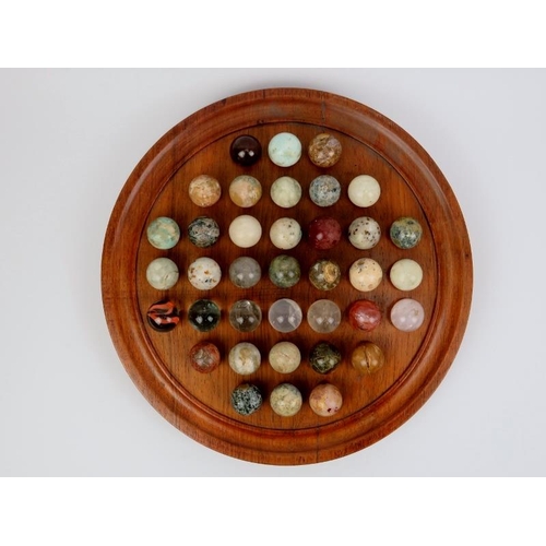 9 - A turned oak Solitaire board with polished specimen stone and glass marbles. Board: 35 cm diameter. ... 