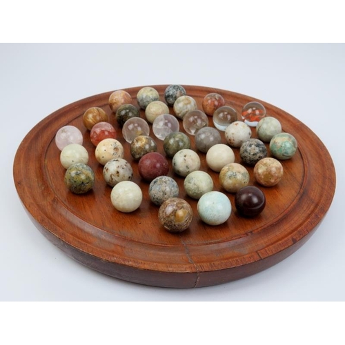 9 - A turned oak Solitaire board with polished specimen stone and glass marbles. Board: 35 cm diameter. ... 