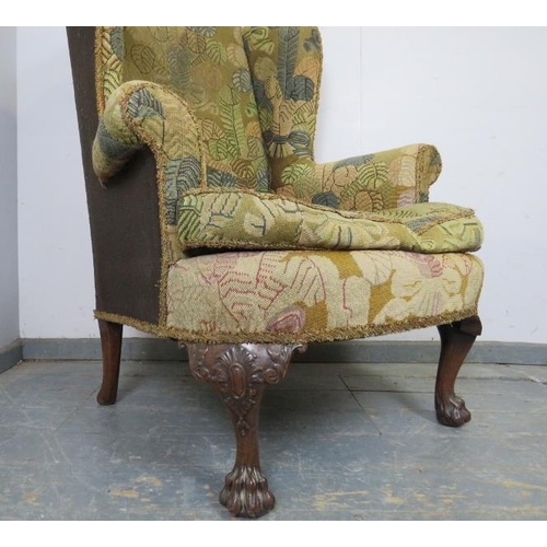 704 - An antique wingback armchair in the George II taste, upholstered in tapestry material, on acanthus c... 