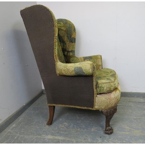 704 - An antique wingback armchair in the George II taste, upholstered in tapestry material, on acanthus c... 