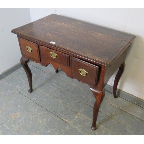 709 - An early 18th century oak lowboy, housing three short drawers with brass handles, above a shaped apr... 