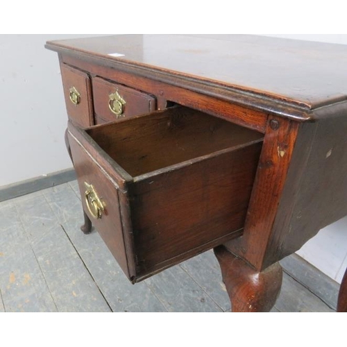 709 - An early 18th century oak lowboy, housing three short drawers with brass handles, above a shaped apr... 