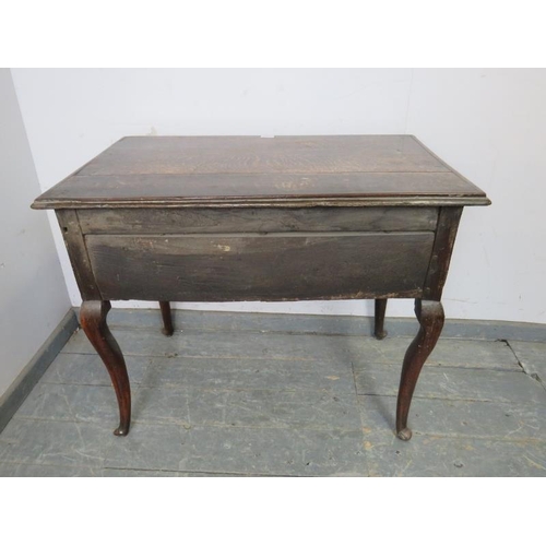 709 - An early 18th century oak lowboy, housing three short drawers with brass handles, above a shaped apr... 