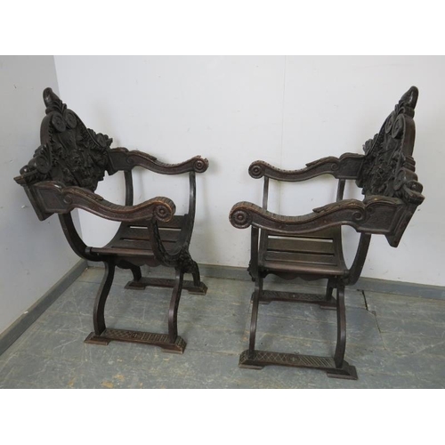 718 - A pair of 19th century oak Savonarola X-frame chairs, ornately carved in the Gothic taste with heral... 