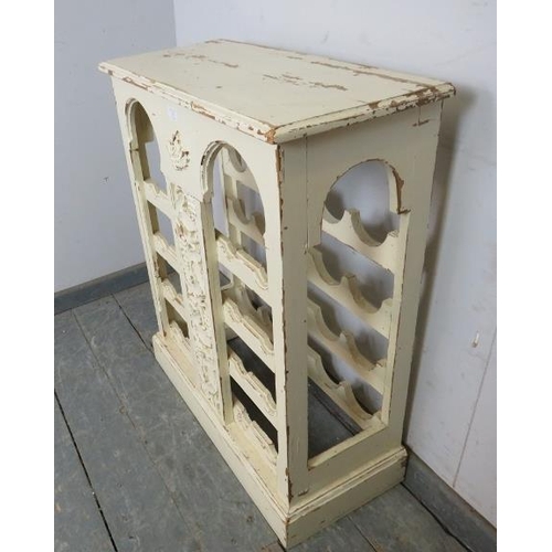 725 - A painted and distressed freestanding wine rack, the relief carved central panel depicting fruiting ... 