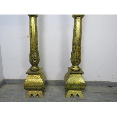 735 - A matched pair of floor-standing giltwood candlesticks, the turned columns with carved acanthus deco... 