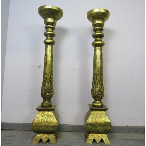 735 - A matched pair of floor-standing giltwood candlesticks, the turned columns with carved acanthus deco... 