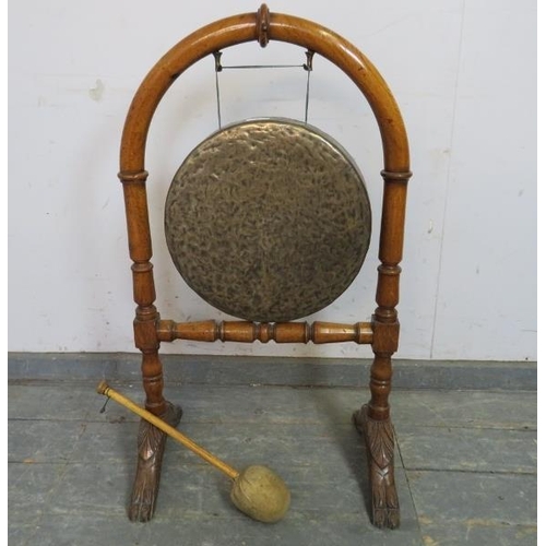 737 - A 19th century brass dinner gong, on an arched golden oak stand with turned stretcher, raised on car... 