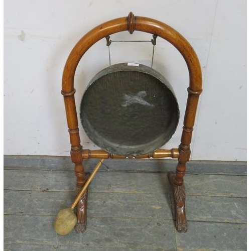 737 - A 19th century brass dinner gong, on an arched golden oak stand with turned stretcher, raised on car... 