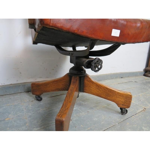 823 - An antique oak swivel and height adjust desk chair, upholstered in burgundy leather with brass studs... 