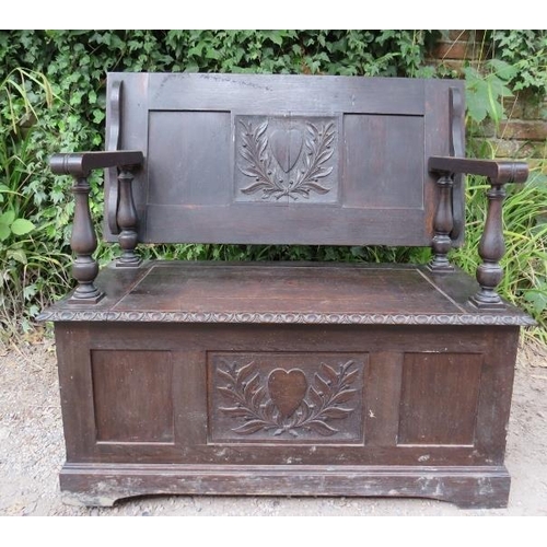 833 - An antique oak monk’s bench in the 17th century taste, the back having relief carved heart motifs fl... 