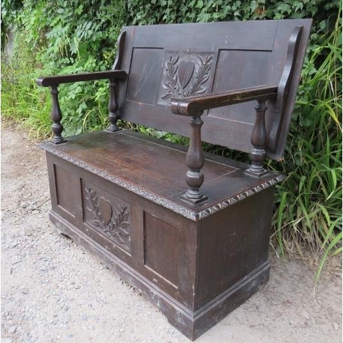 833 - An antique oak monk’s bench in the 17th century taste, the back having relief carved heart motifs fl... 