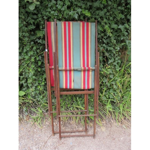 847 - A pair of vintage folding deckchairs, the beech frames with multicoloured striped canvas seats. 
H84... 