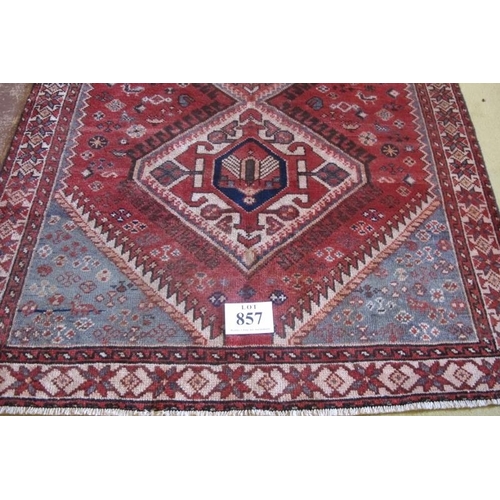 857 - A good quality Persian Heriz rug with three interlocking diamond motifs on a plane red ground.  205c... 