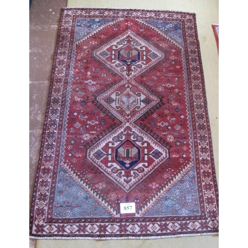 857 - A good quality Persian Heriz rug with three interlocking diamond motifs on a plane red ground.  205c... 