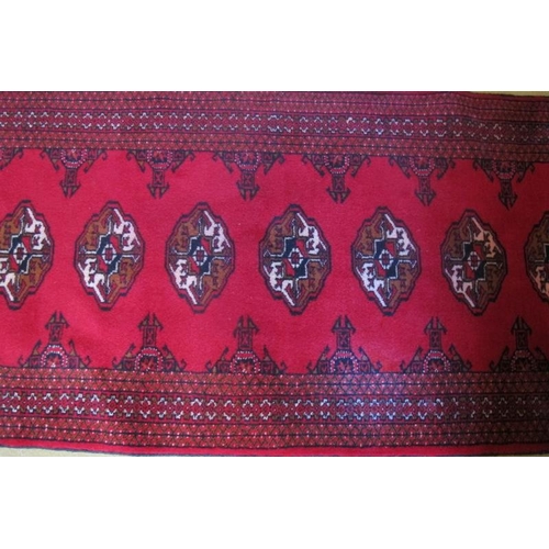 864 - North East Persian Turkoman runner.  14 repeat patter medallions on a deep red ground.  280cm x 80cm... 