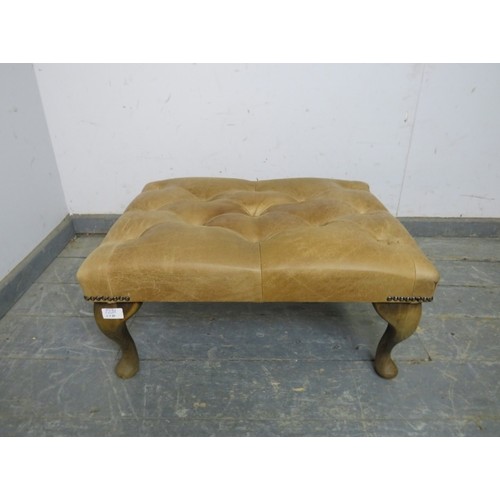 720A - An antique style footstool, upholstered in buttoned tan leather with brass studs, on cabriole suppor... 