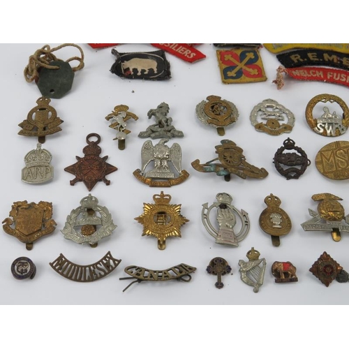 37 - Militaria: A collection of mainly WWI and WWII period British military cap badges, buttons and relat... 